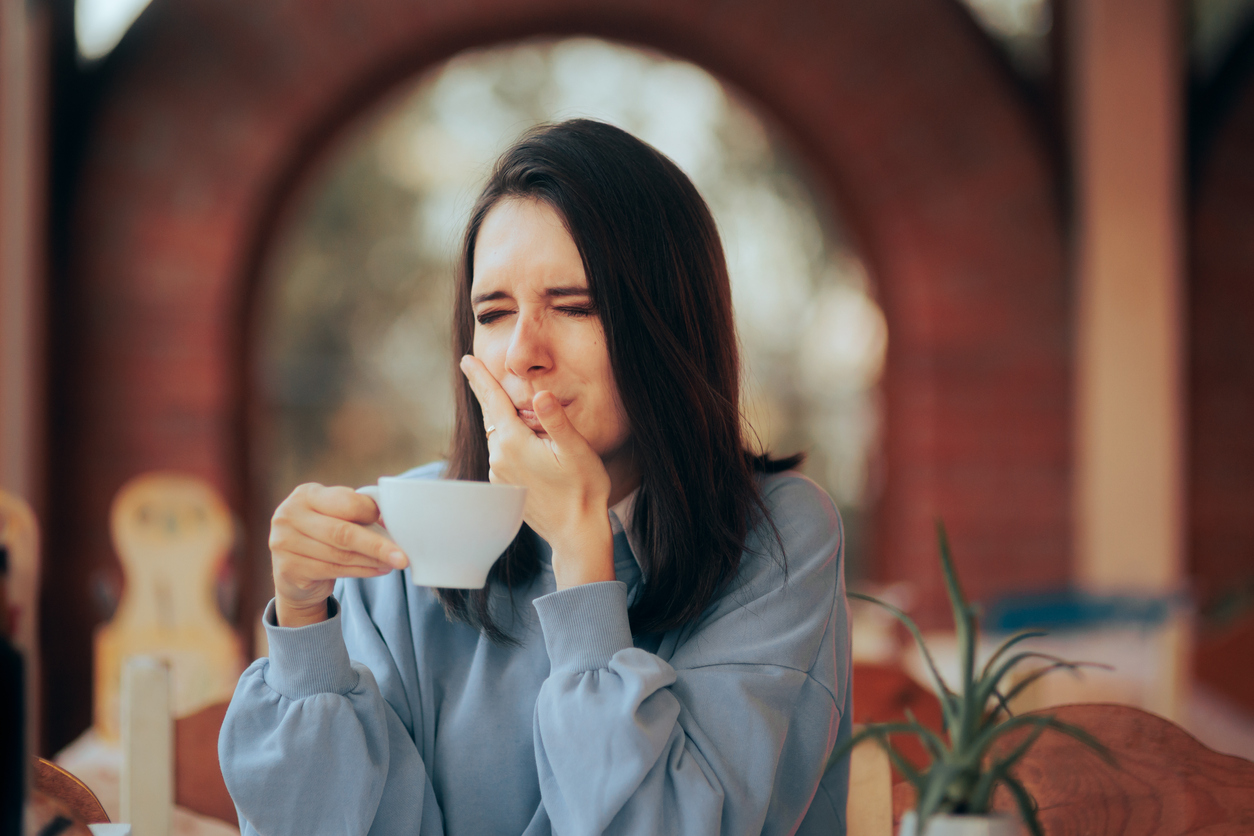 Understanding Tooth Sensitivity: Causes, Symptoms, and Treatment Options, Young person feeling discomfort from having a hot beverage